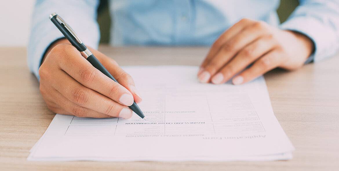 a photo of hands signing a form.