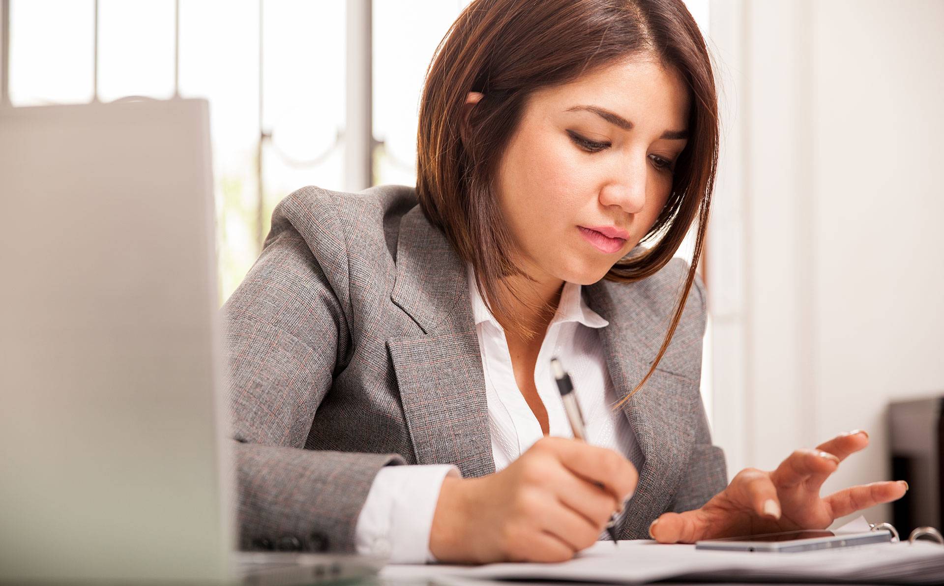 A woman uses a calculator and writes on a paper.