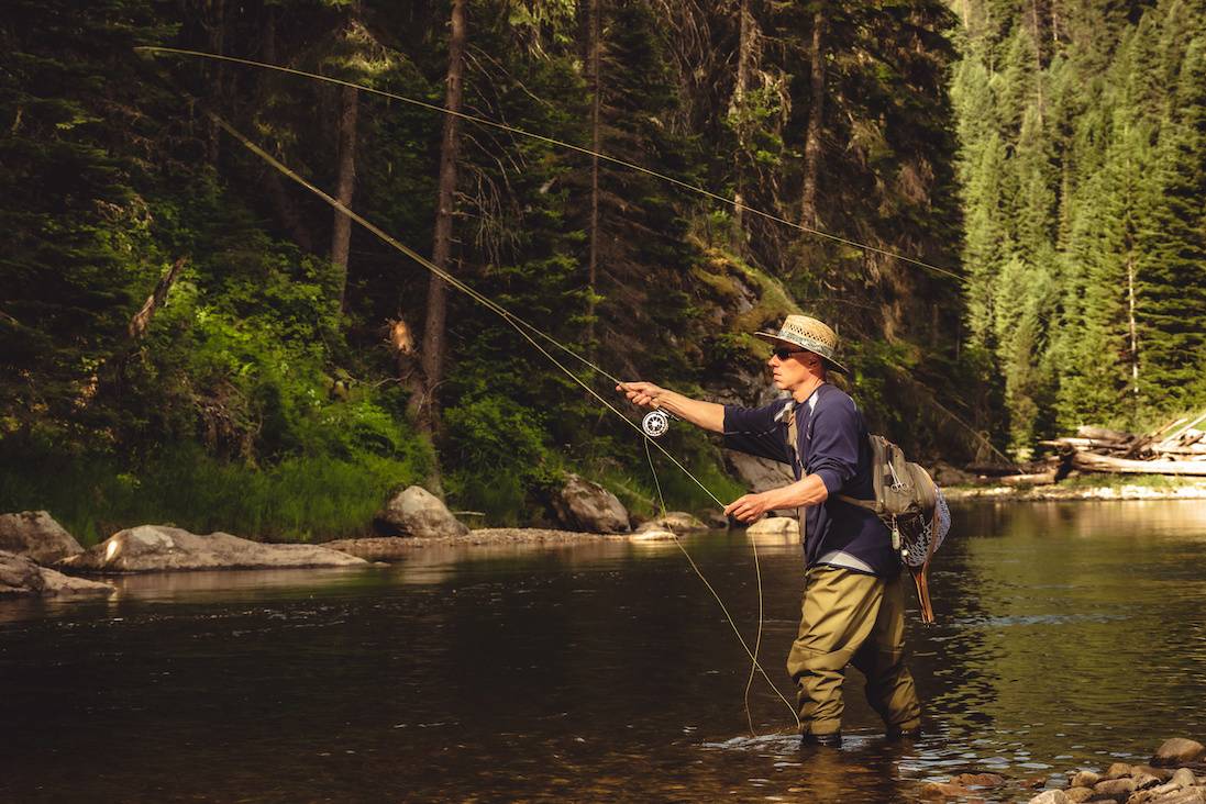 person fly fishing in a river image