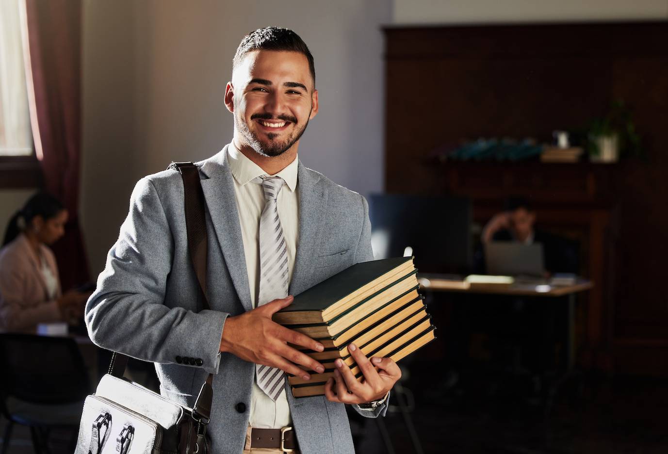 Law student holding law books and smiling at the camera