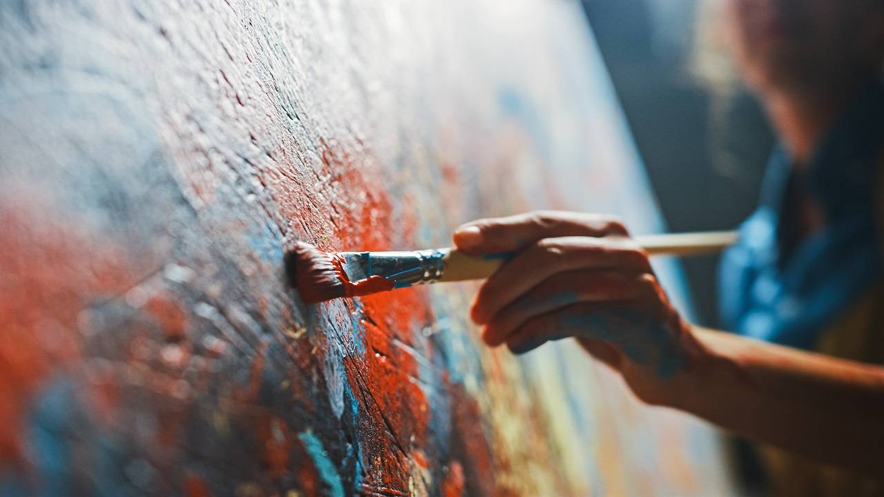 Abstract painting with a man holding a paint brush to the canvas.