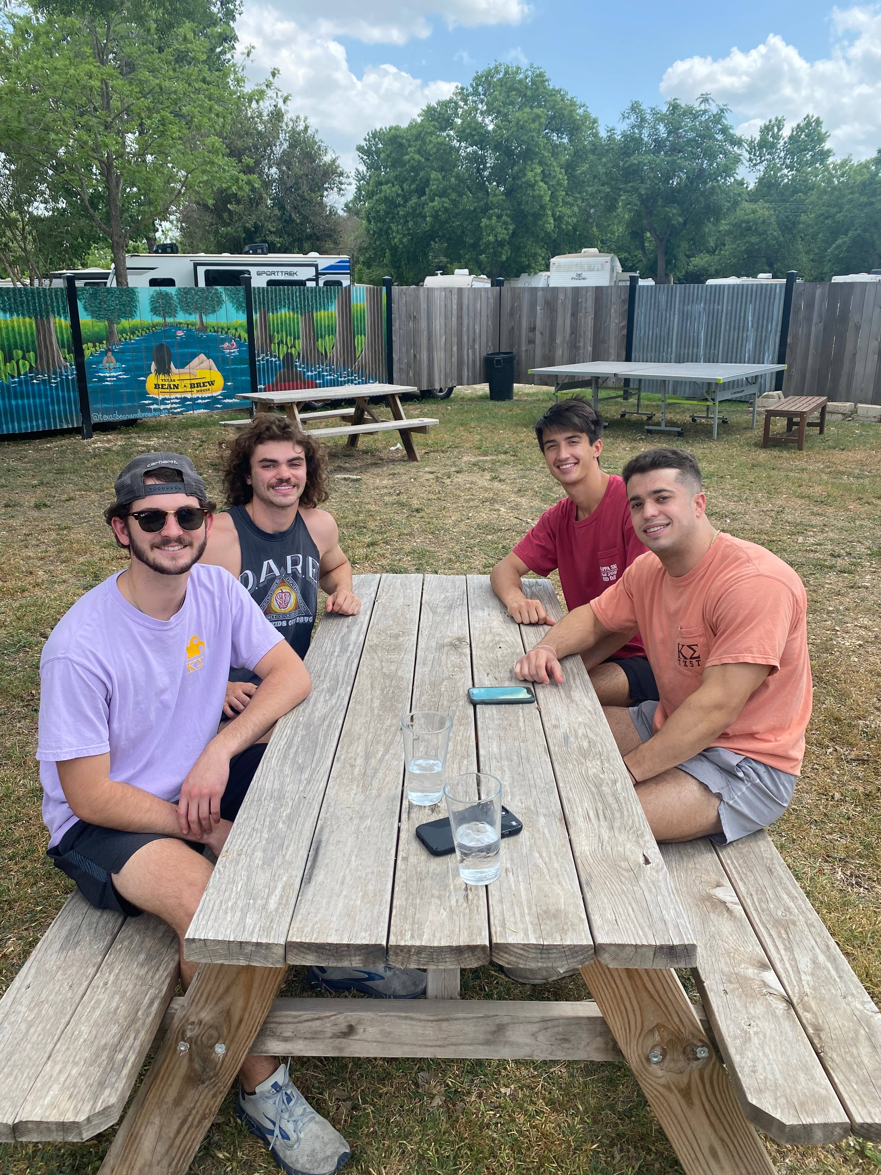 Four men in Kappa Sigma sit at a picnic table outside