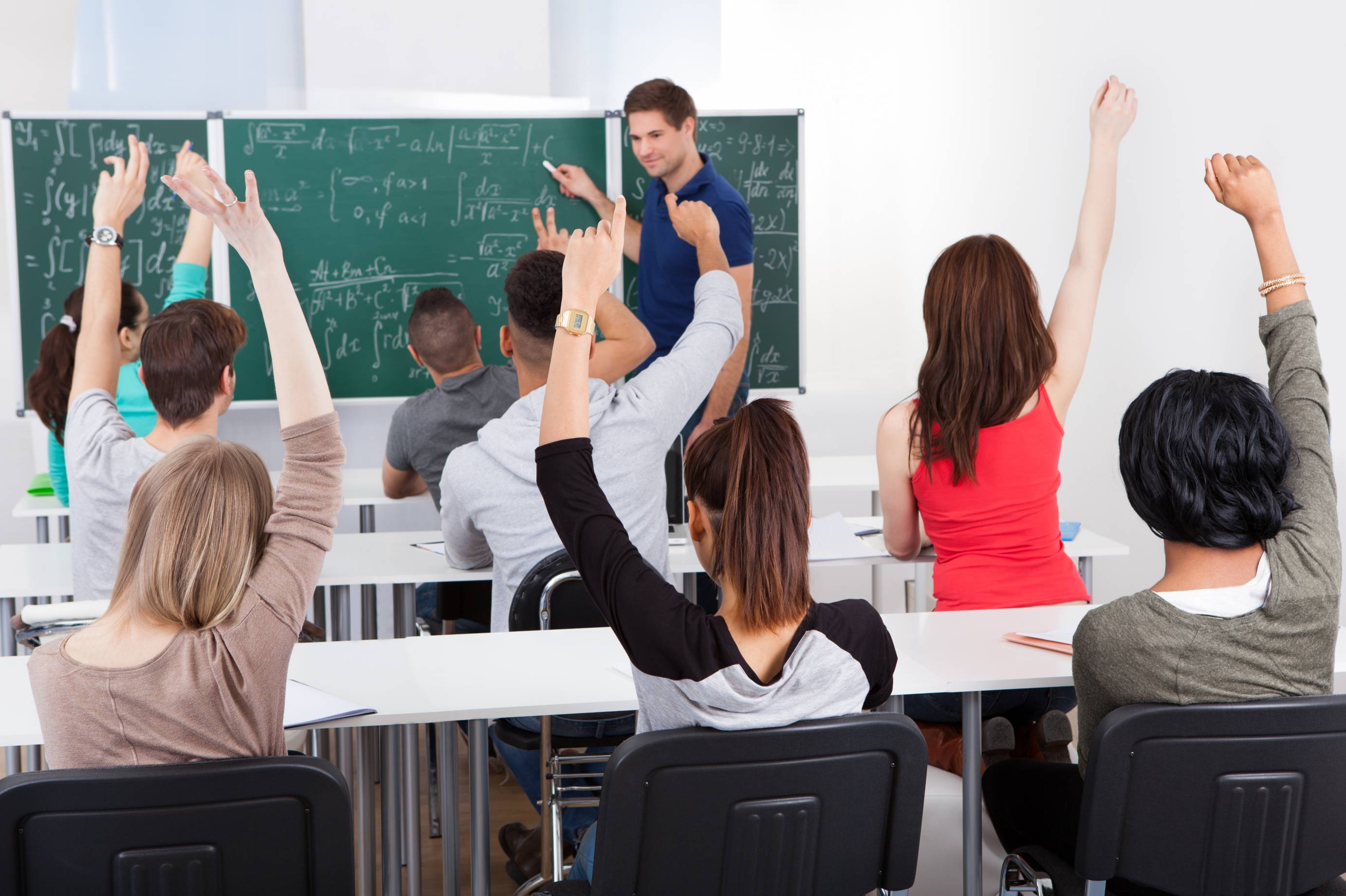 students in classroom raising hands to answer mathematics question