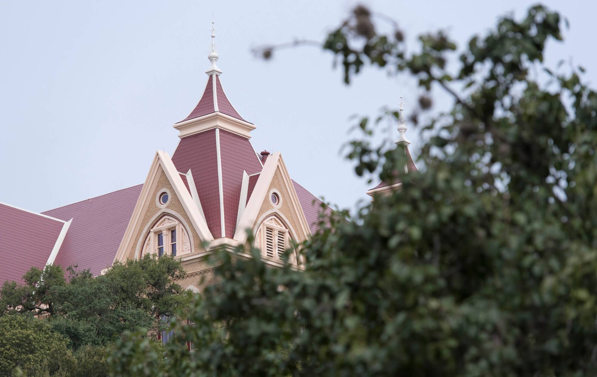 the red roof of old main through a group of trees