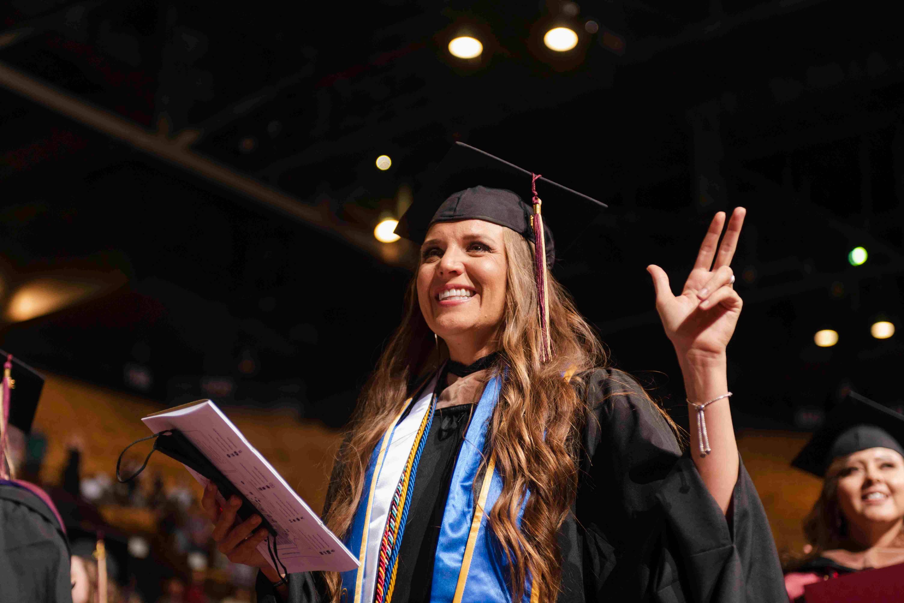a student holds up the Texas State hand sign during a commencement ceremony