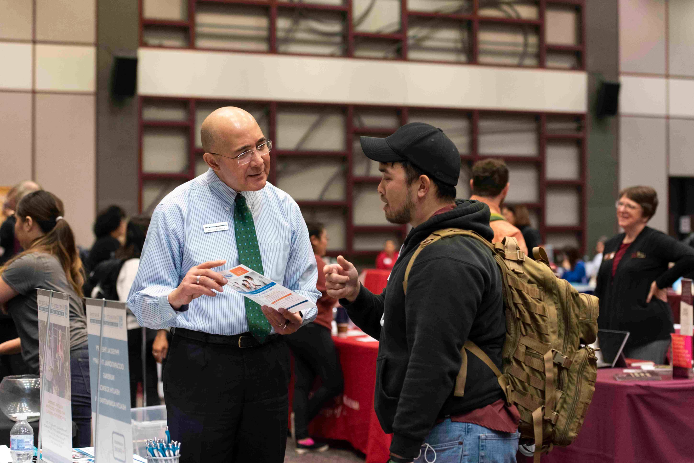 a professor and student share a conversation during a fair