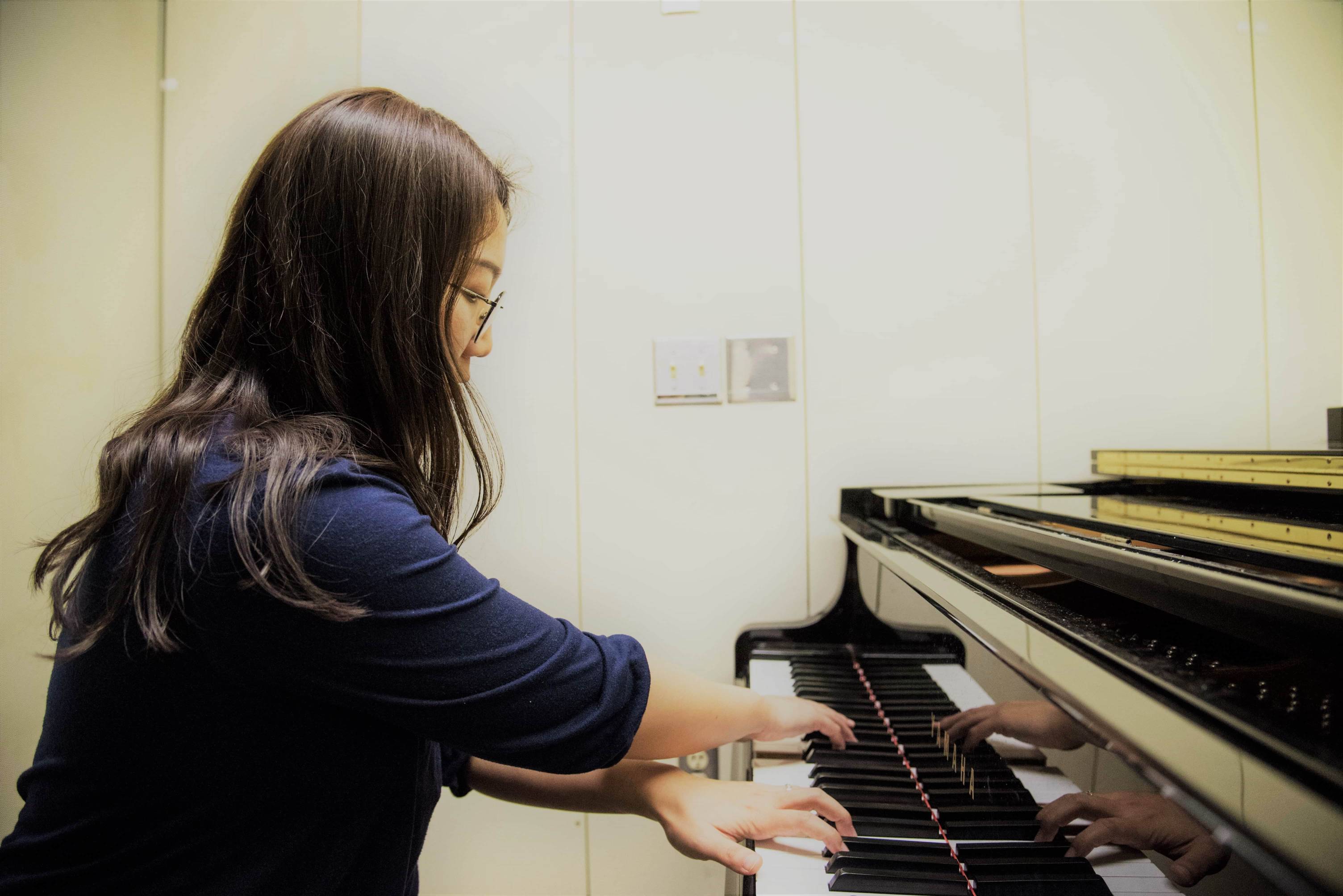 a student sits and play the piano