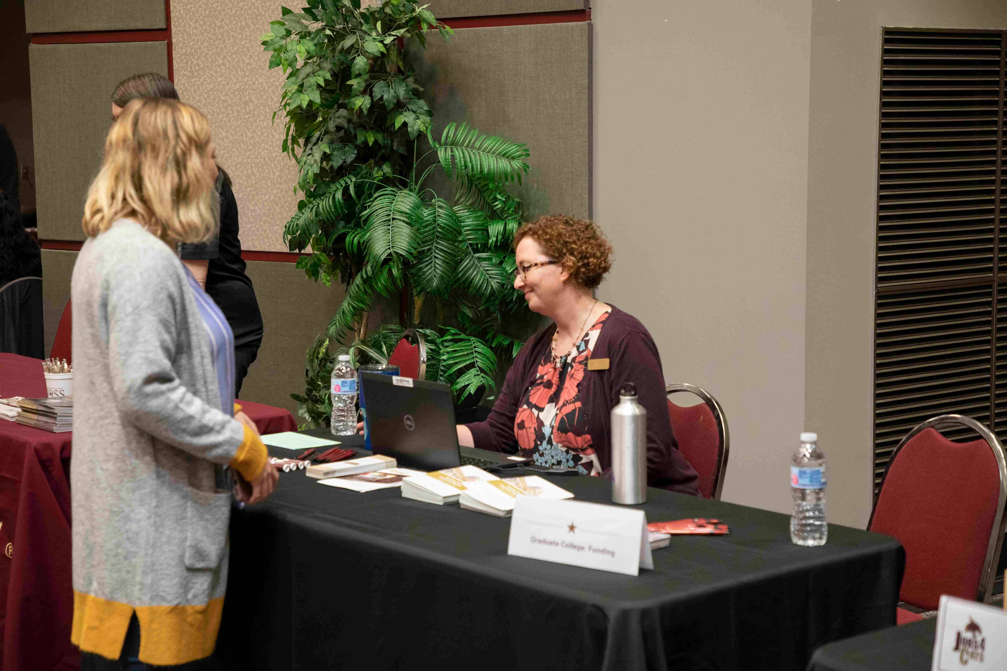 a students stands at an external funding table with dr. andrea hilkovitz