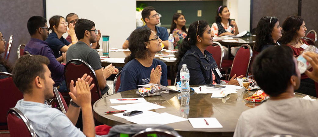 a group of international students sit at a round table during a presentation
