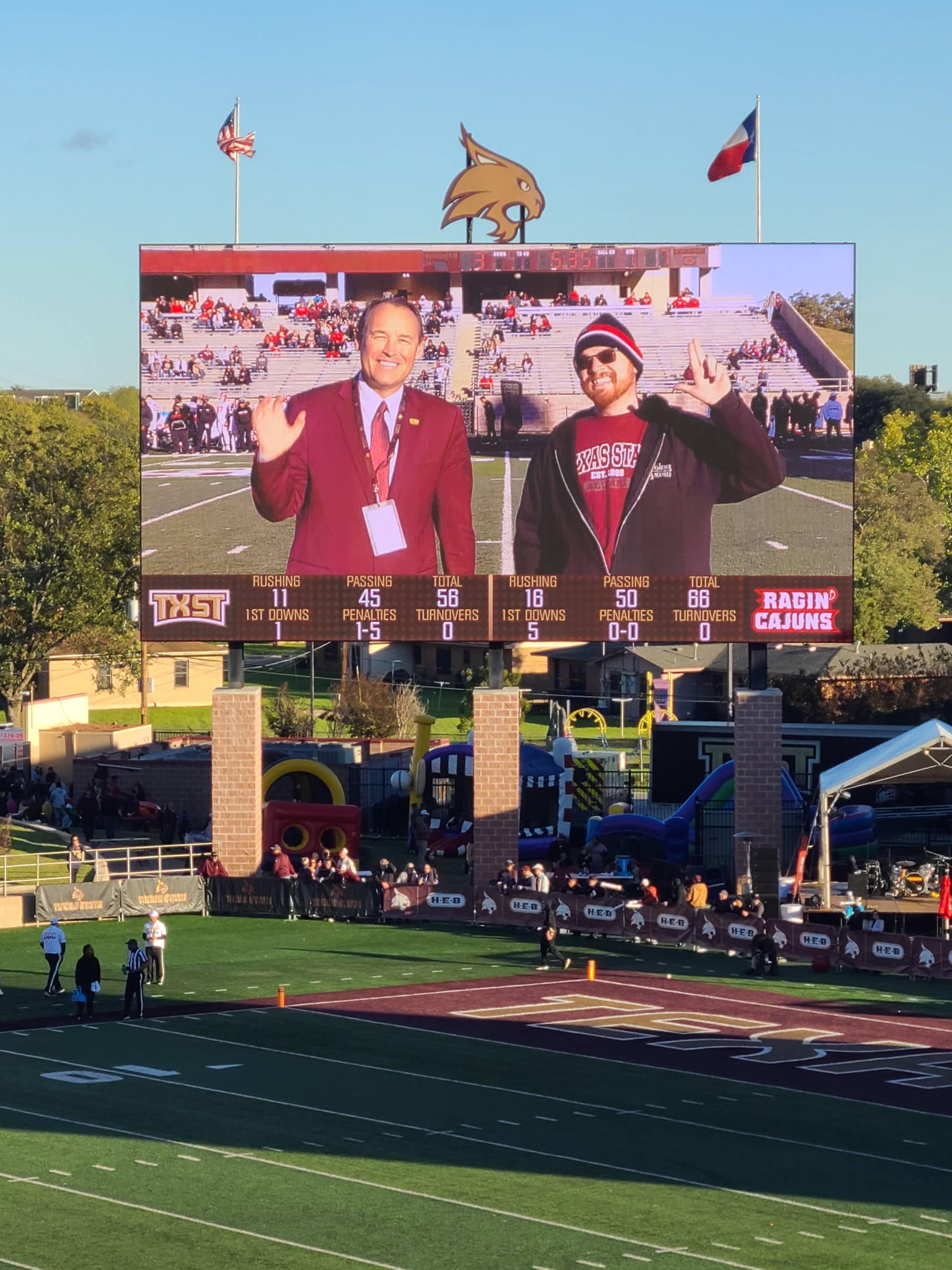 Photo of President Damphousse and Mark Moore on the jumbo screen at Bobcat Stadium during a TXST football game.