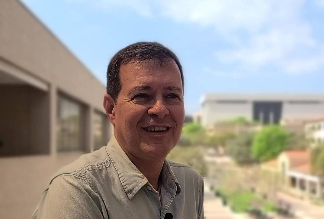 Humerto Santos smiling with a view of campus and Alkek in the background