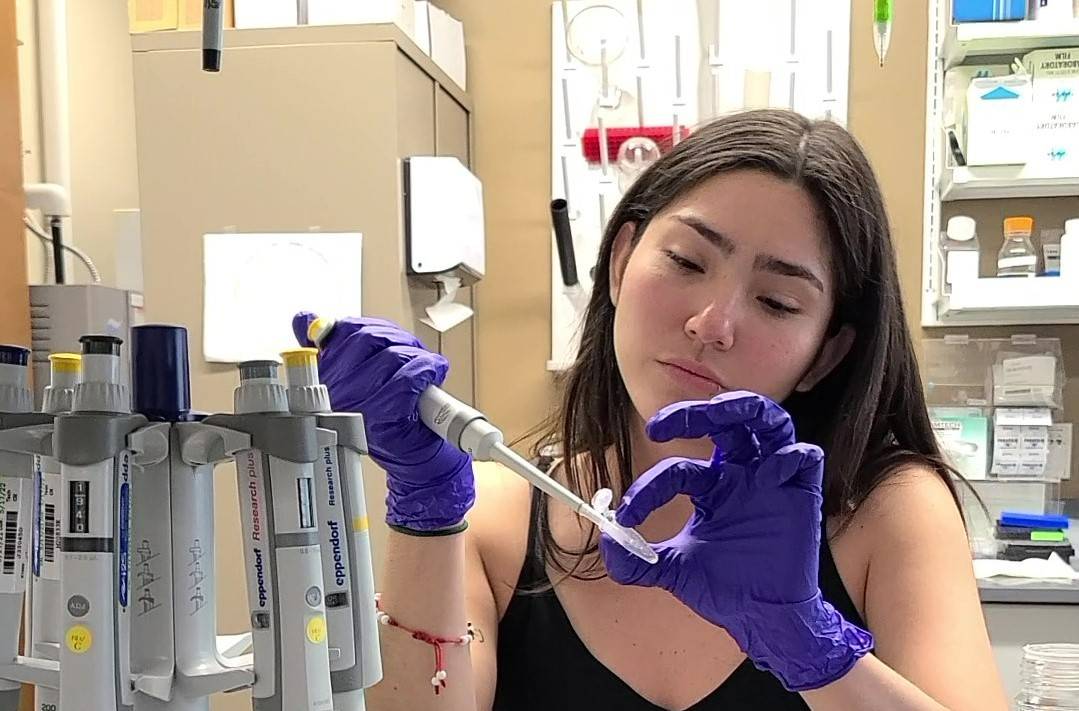 Mar Moretta sitting at a counter in a lab holding a syring