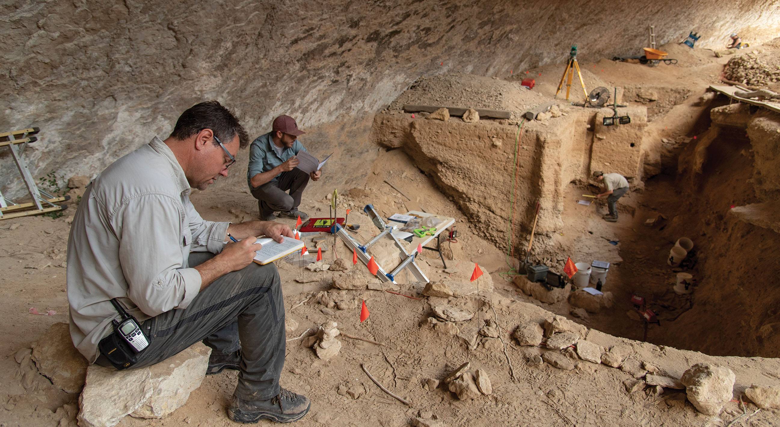 archeologist writing next to dig site