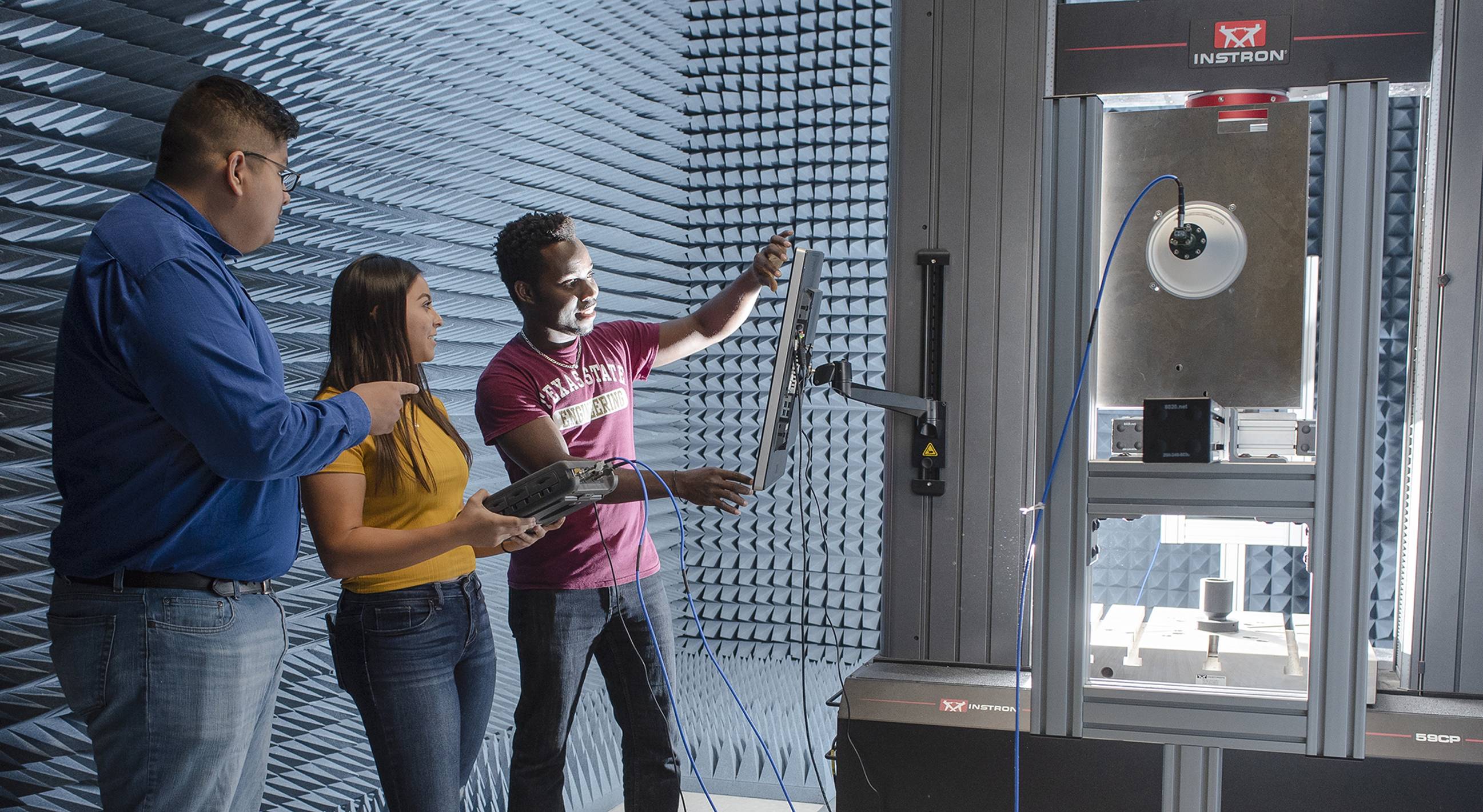 three people looking at large piece of machinery