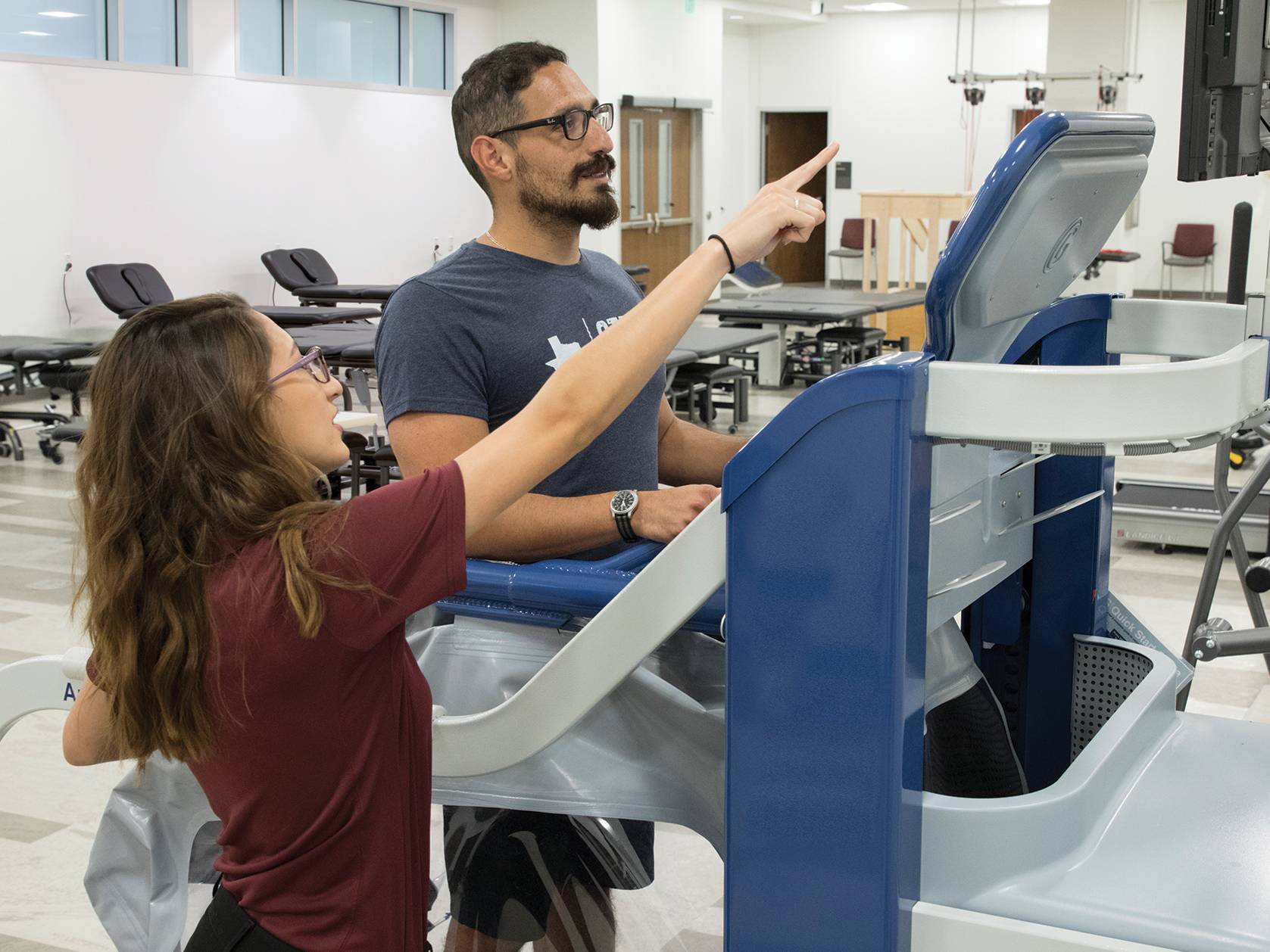 physical therapist working with patient on machine