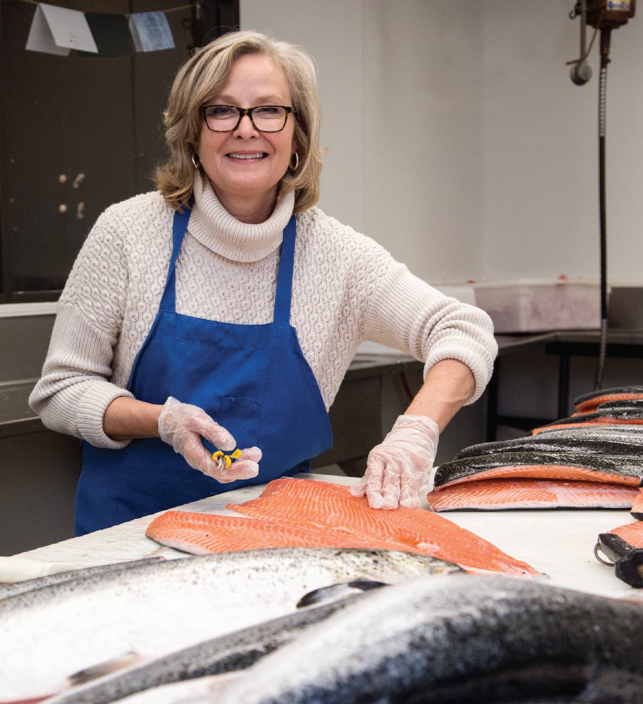 women cleans and prepares fish in kitchen