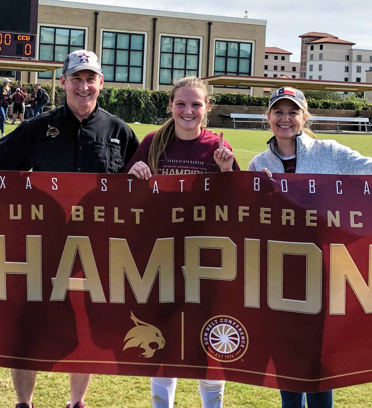 family smiling holding championship banner