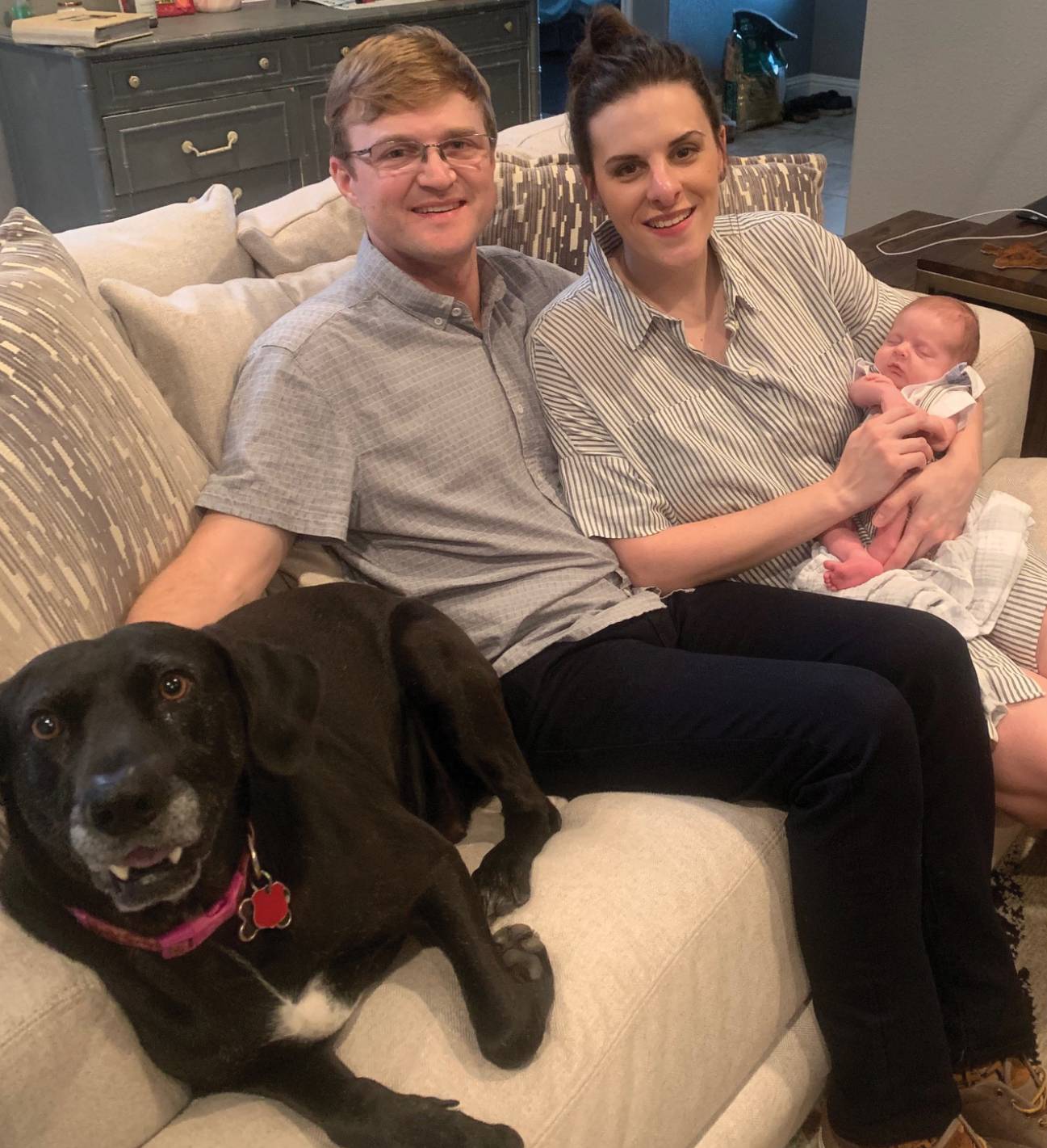 young couple smiling with baby and dog