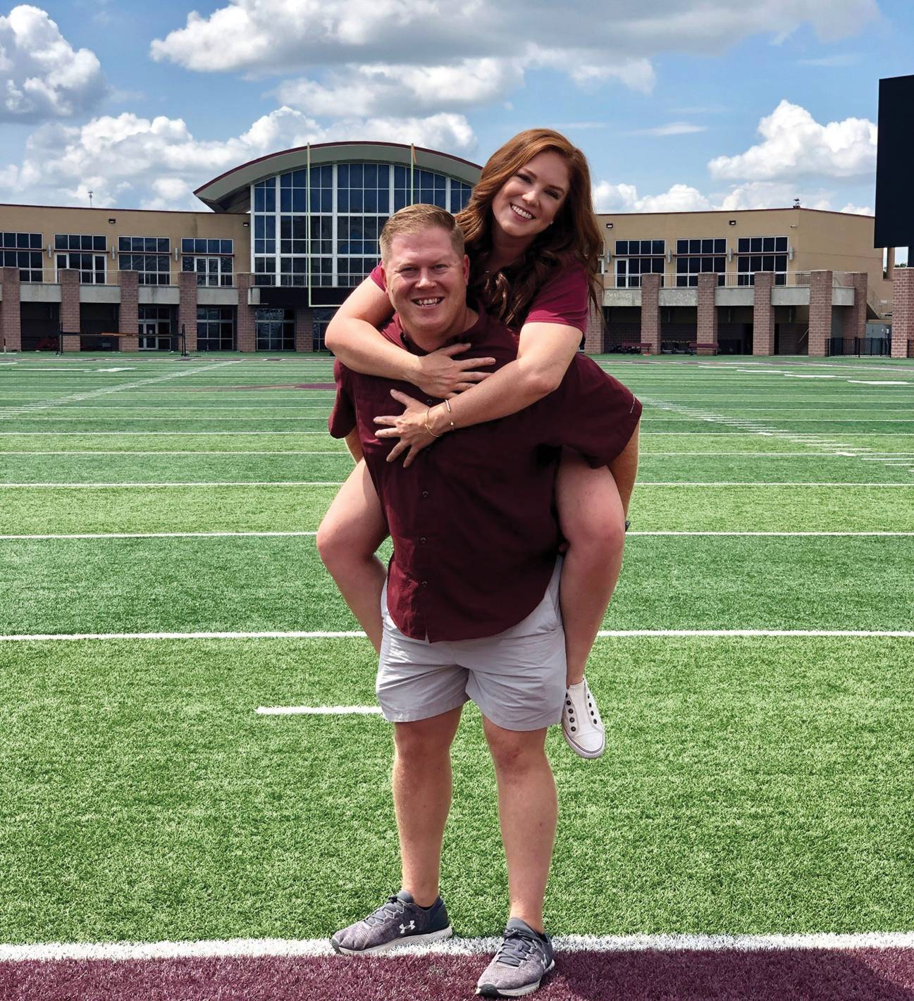 young couple smiling on football field