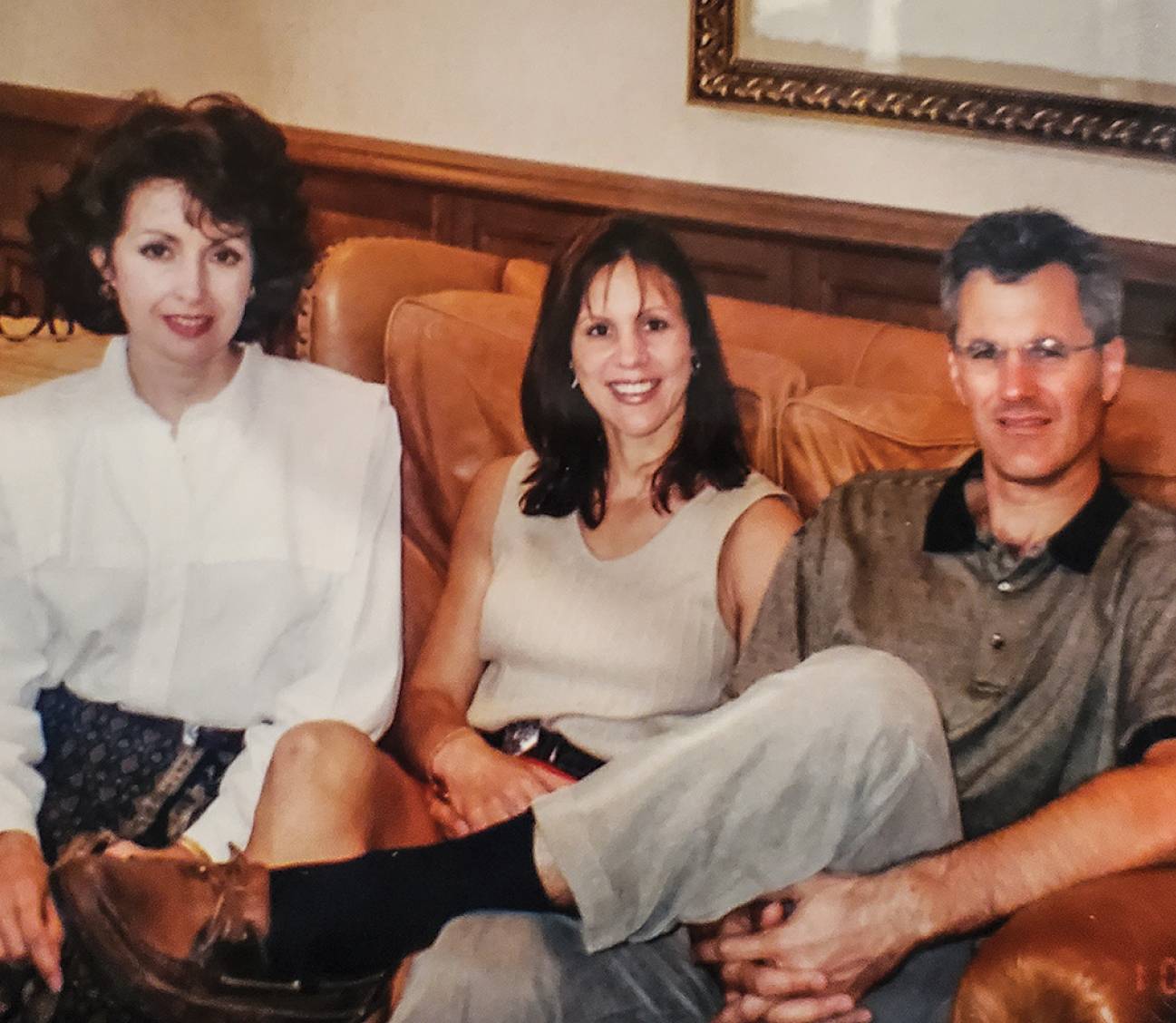 three people smiling while sitting on couch