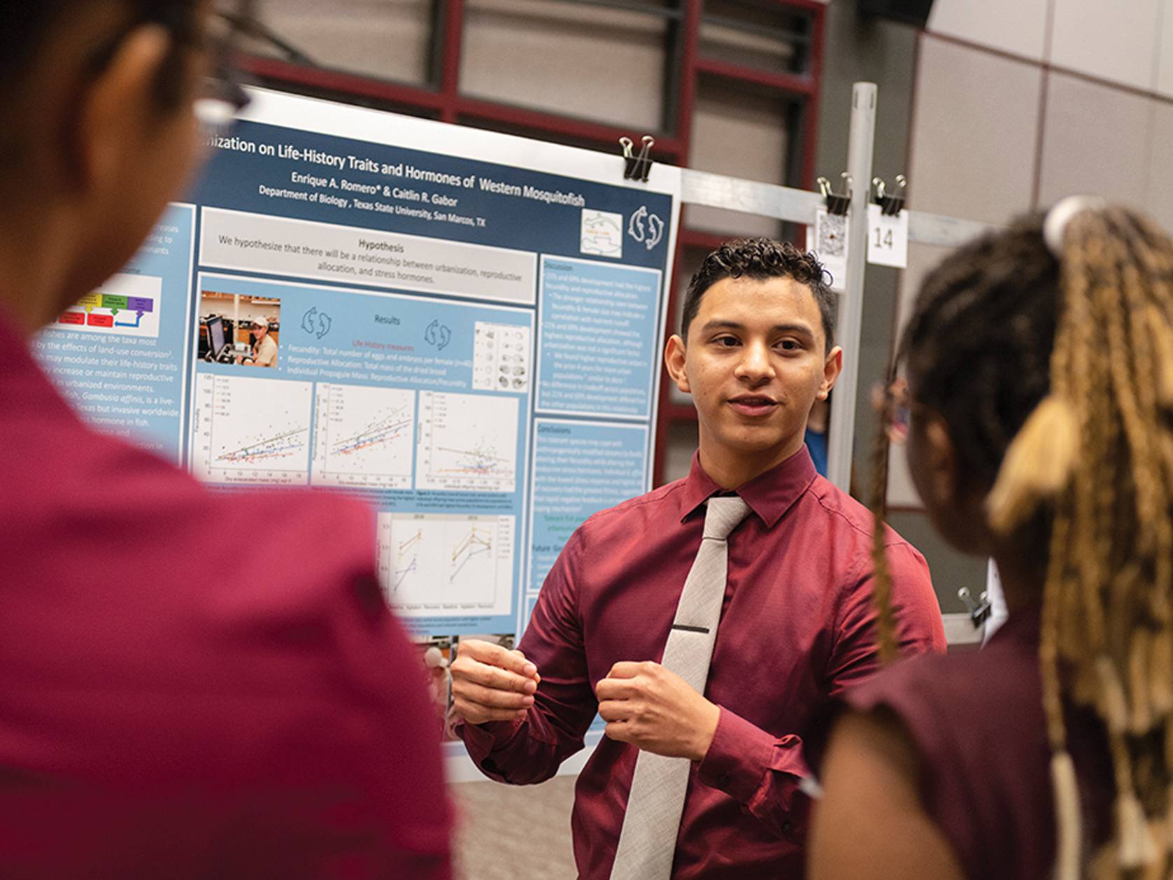 male student giving poster presentation