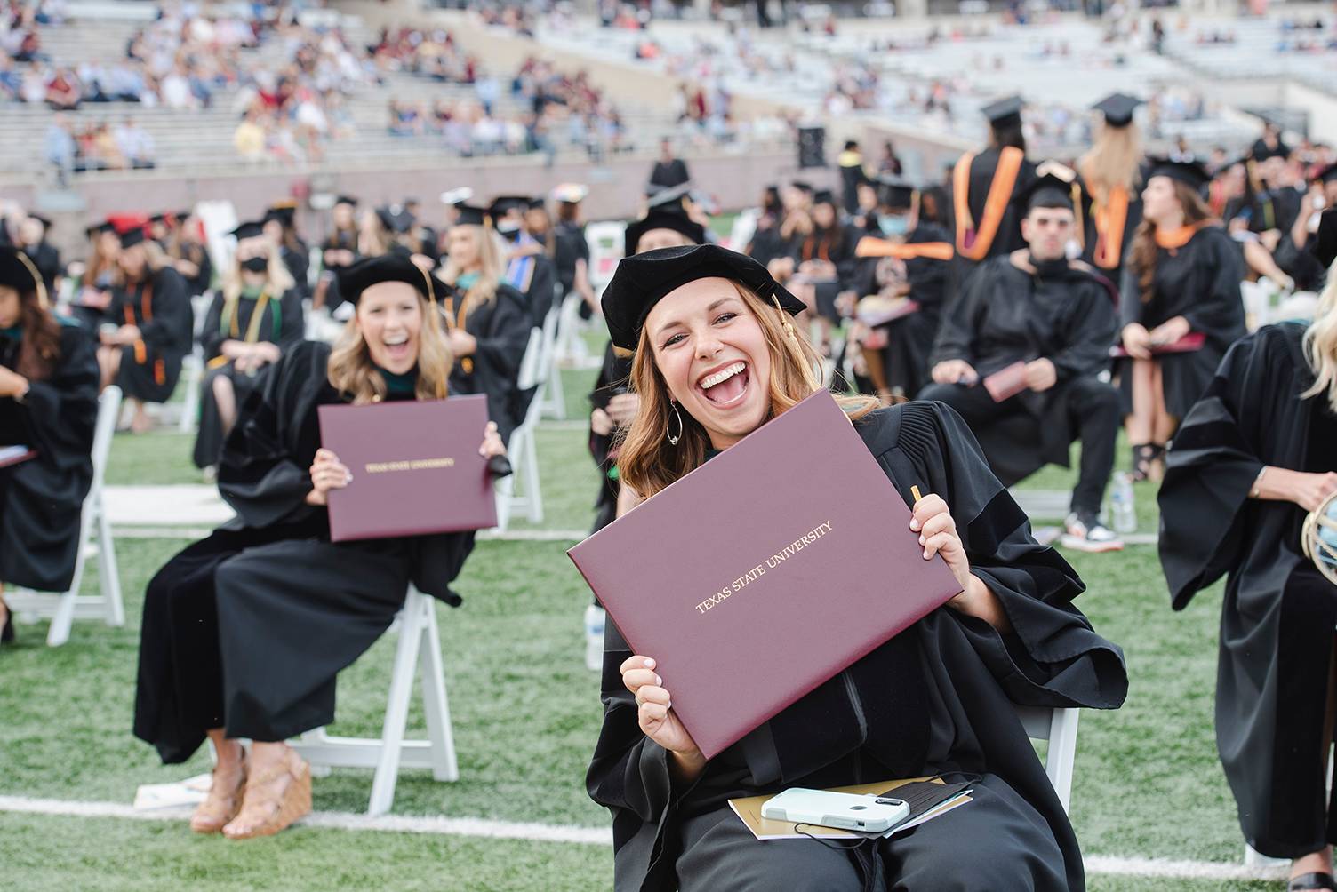 two females holding diplomas and smiling