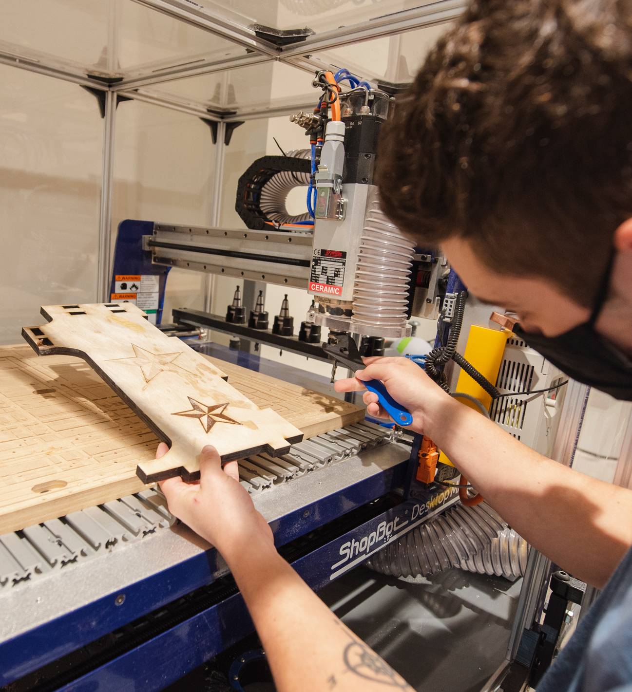 male student working with wood burning machine