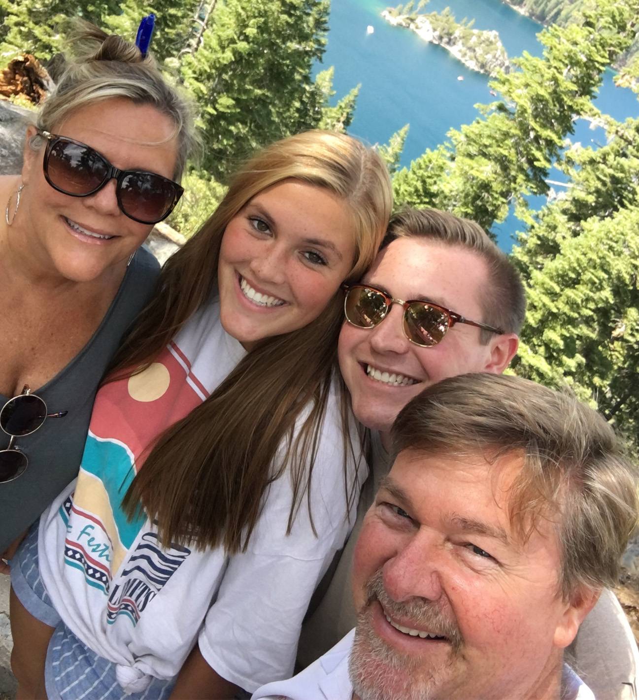 four family members smiling in front of lake and trees