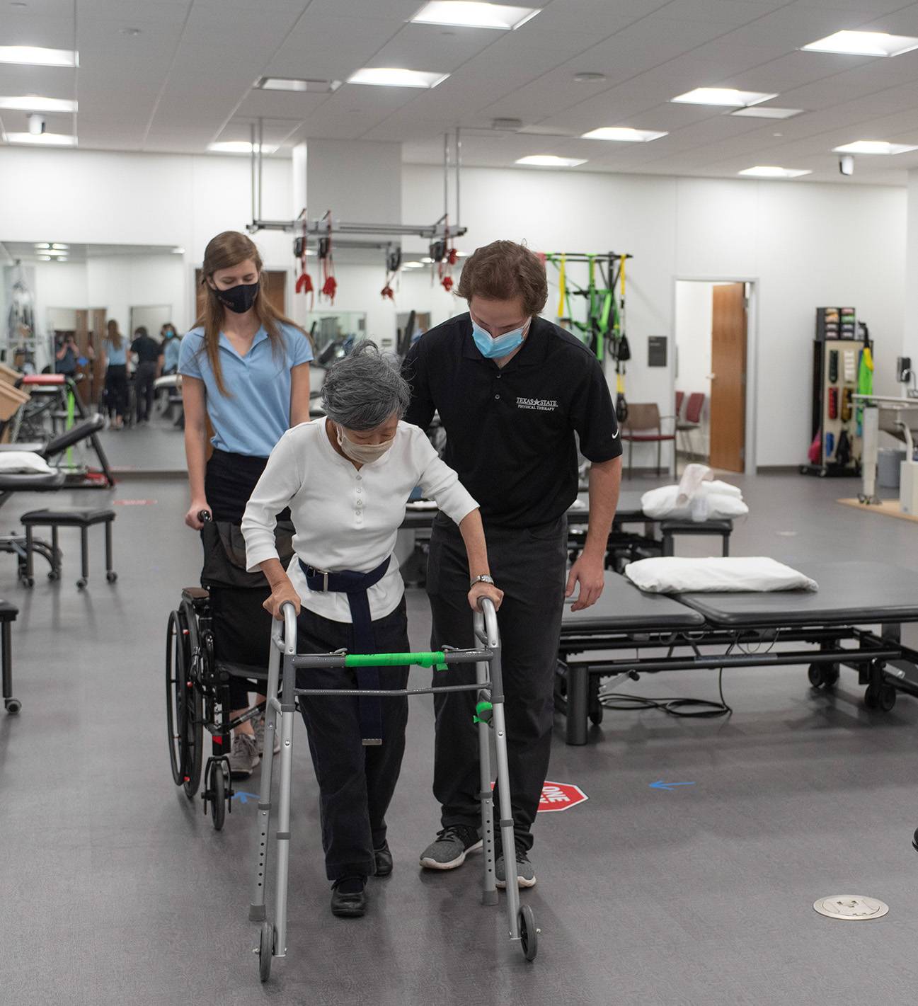 woman with walker being assisted by physical therapist