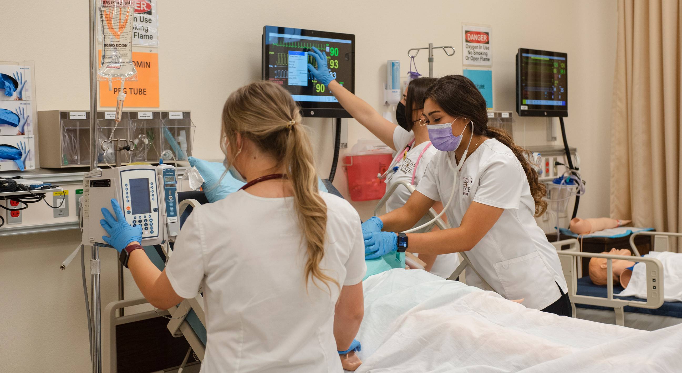 nursing students working with patient in hospital bed