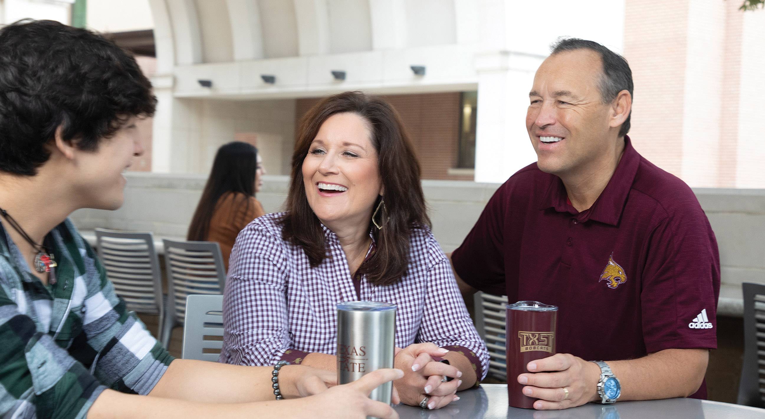 TXST President Kelly Damphousse and wife Beth Damphousse on campus talking to a male student.