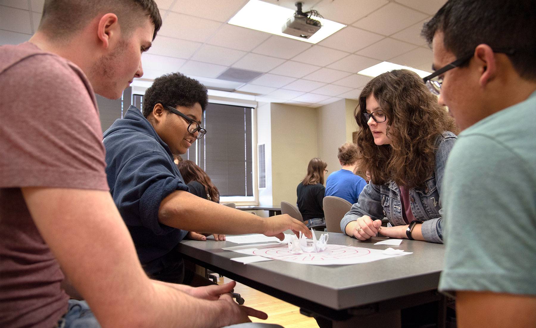 Four students sitting at a table looking at papers