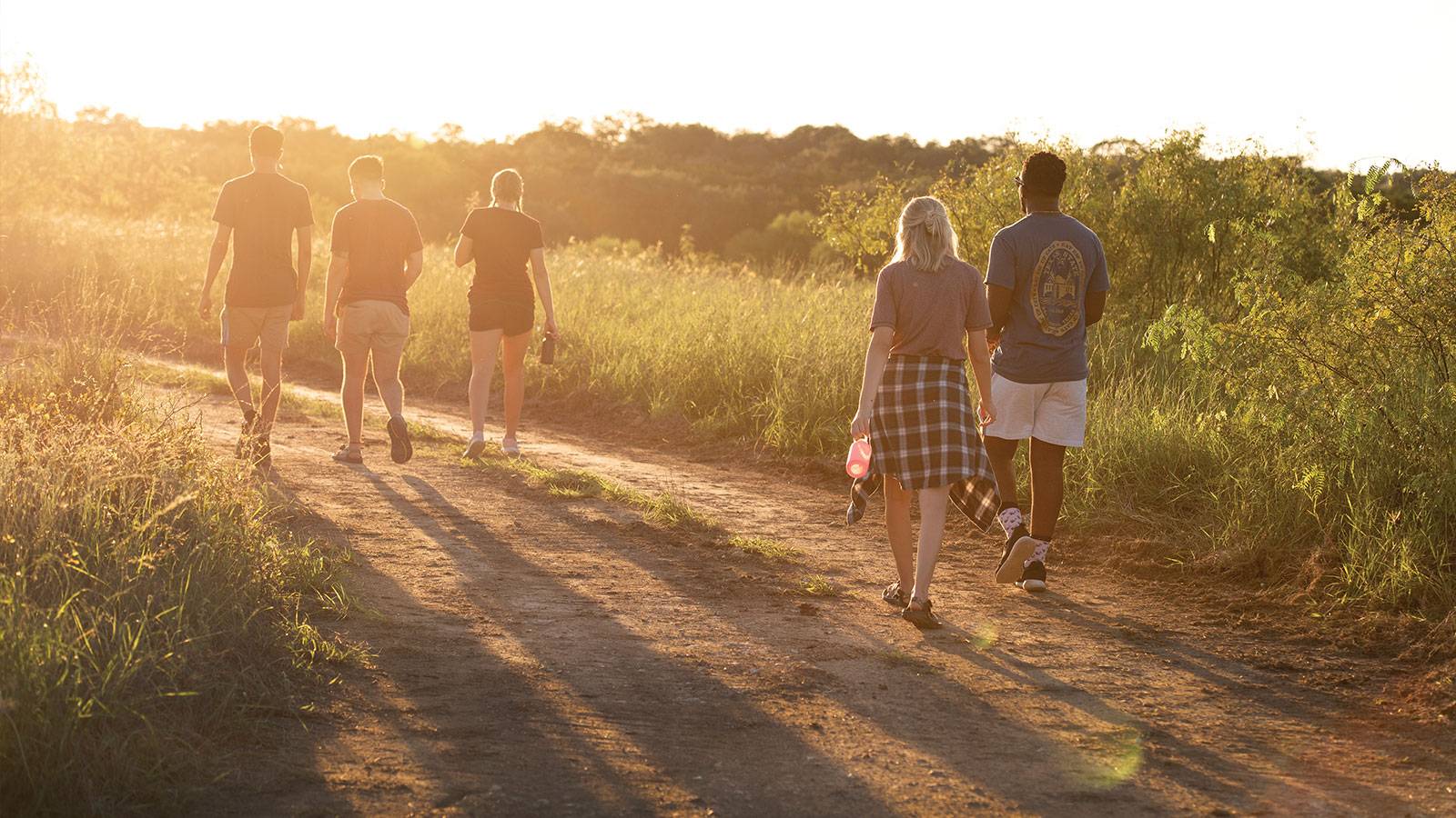 Students hiking San Marcos trails as the sun sets ahead
