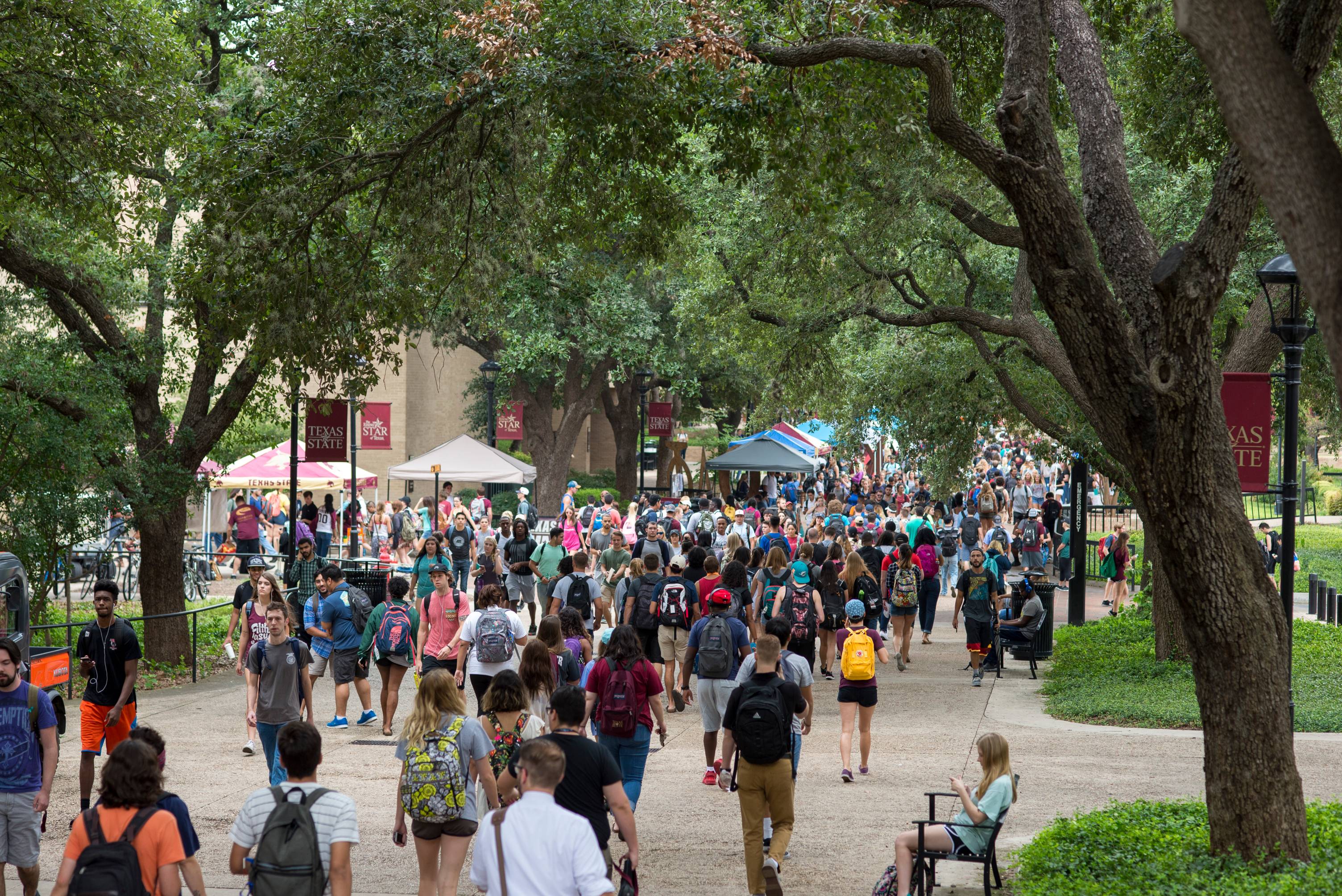 students walking through the TXST quad with booths setup