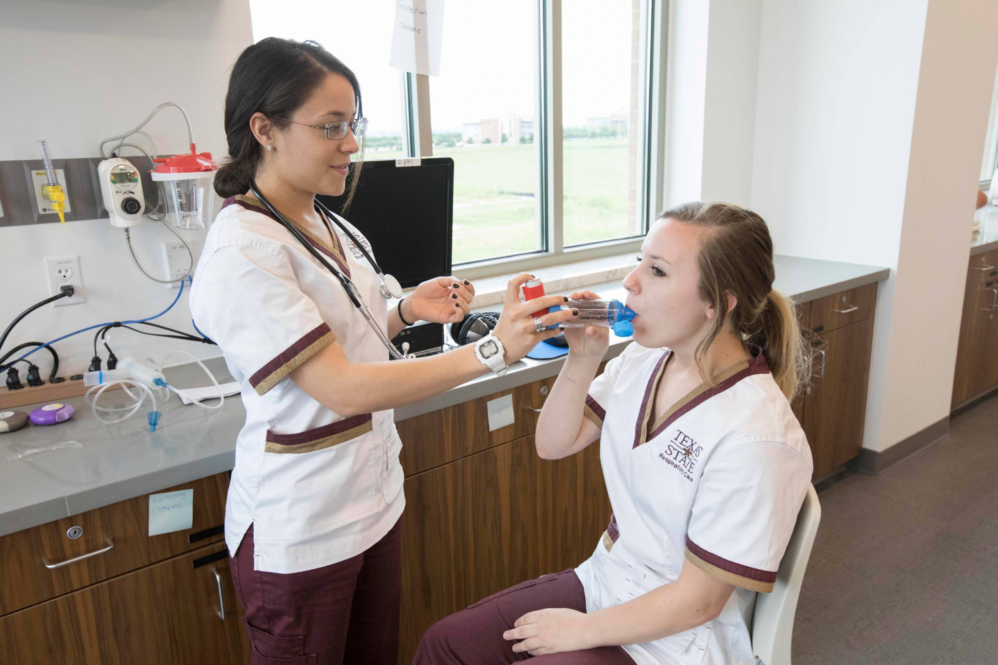 two students practice using a respiratory care tool