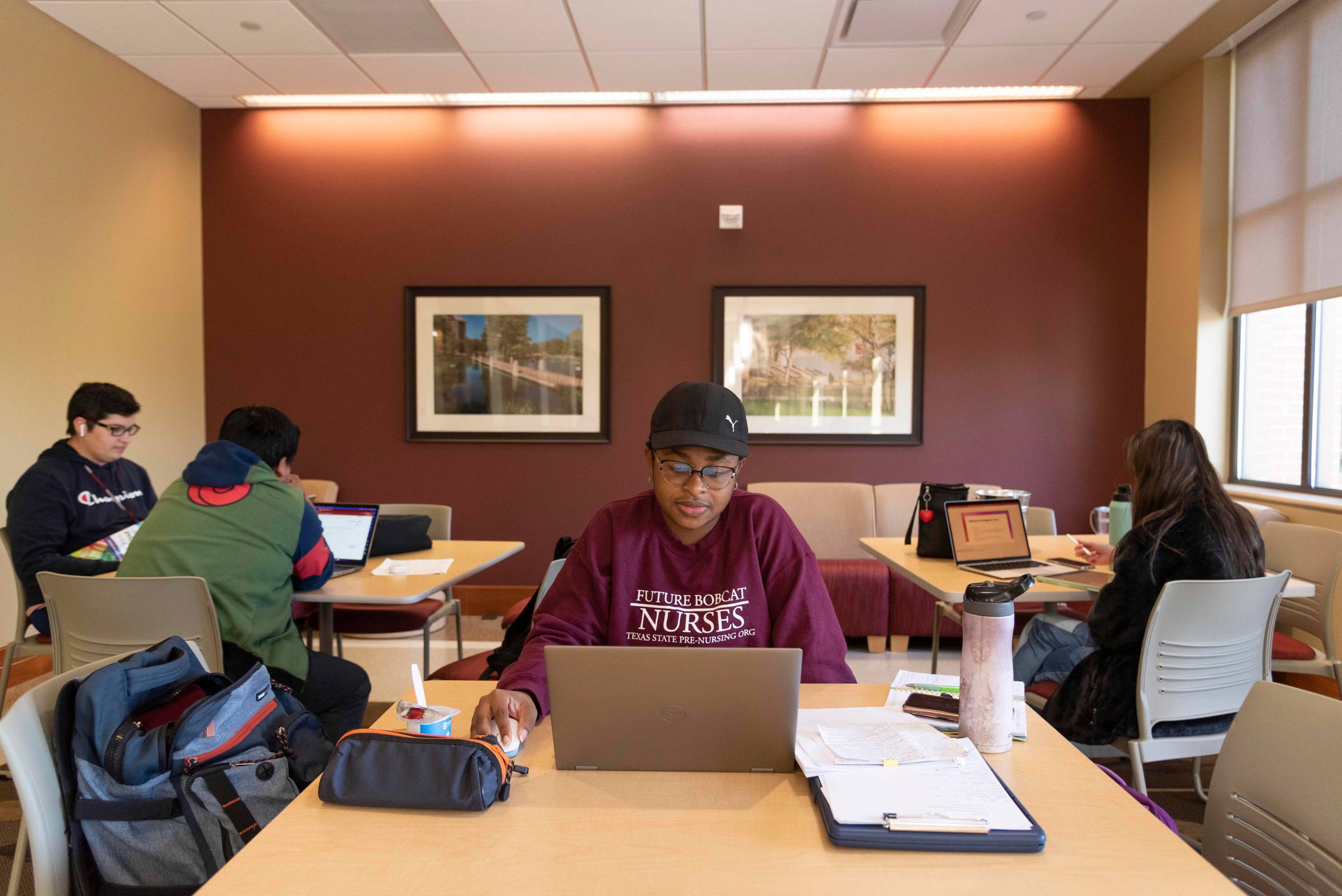 a nursing student sits in a study area while working on her laptop