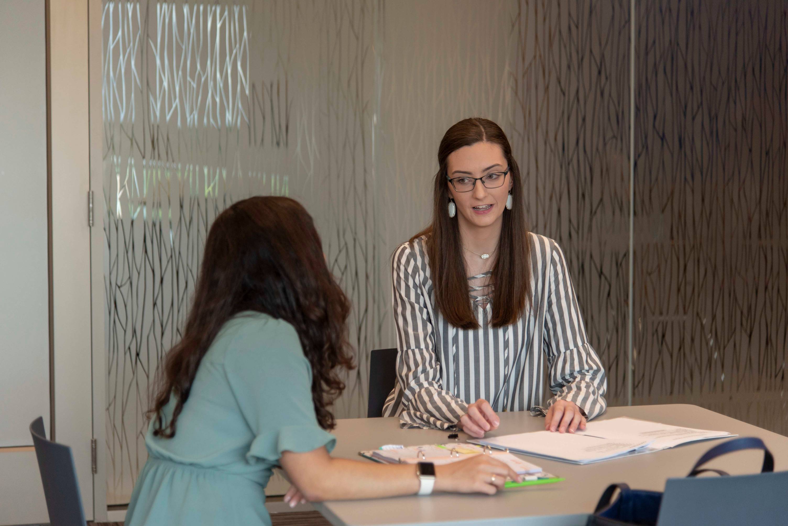 two students sit at a table in a study room having a discussion