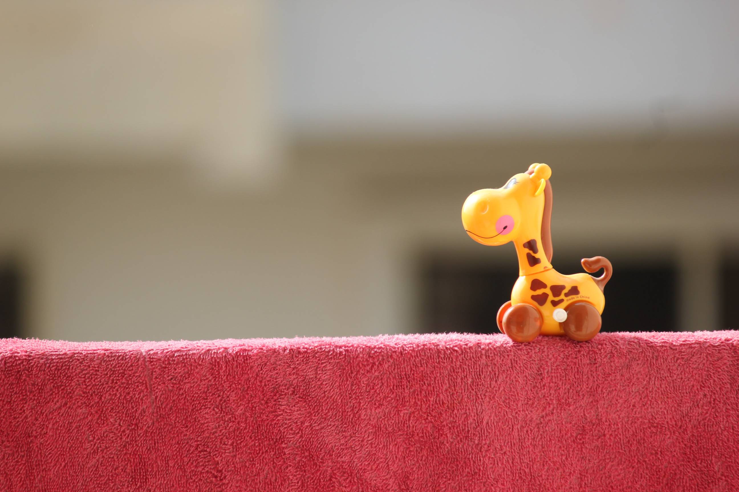 toy giraffe on back of red couch