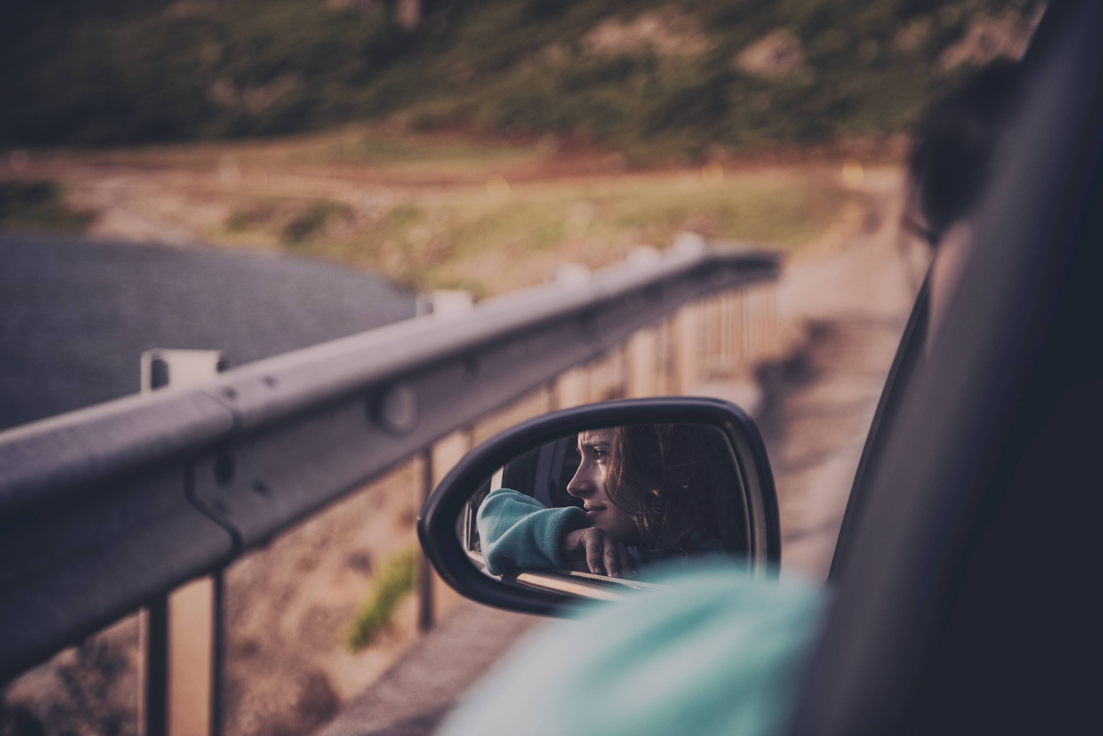 woman's reflection in vehicle side mirror