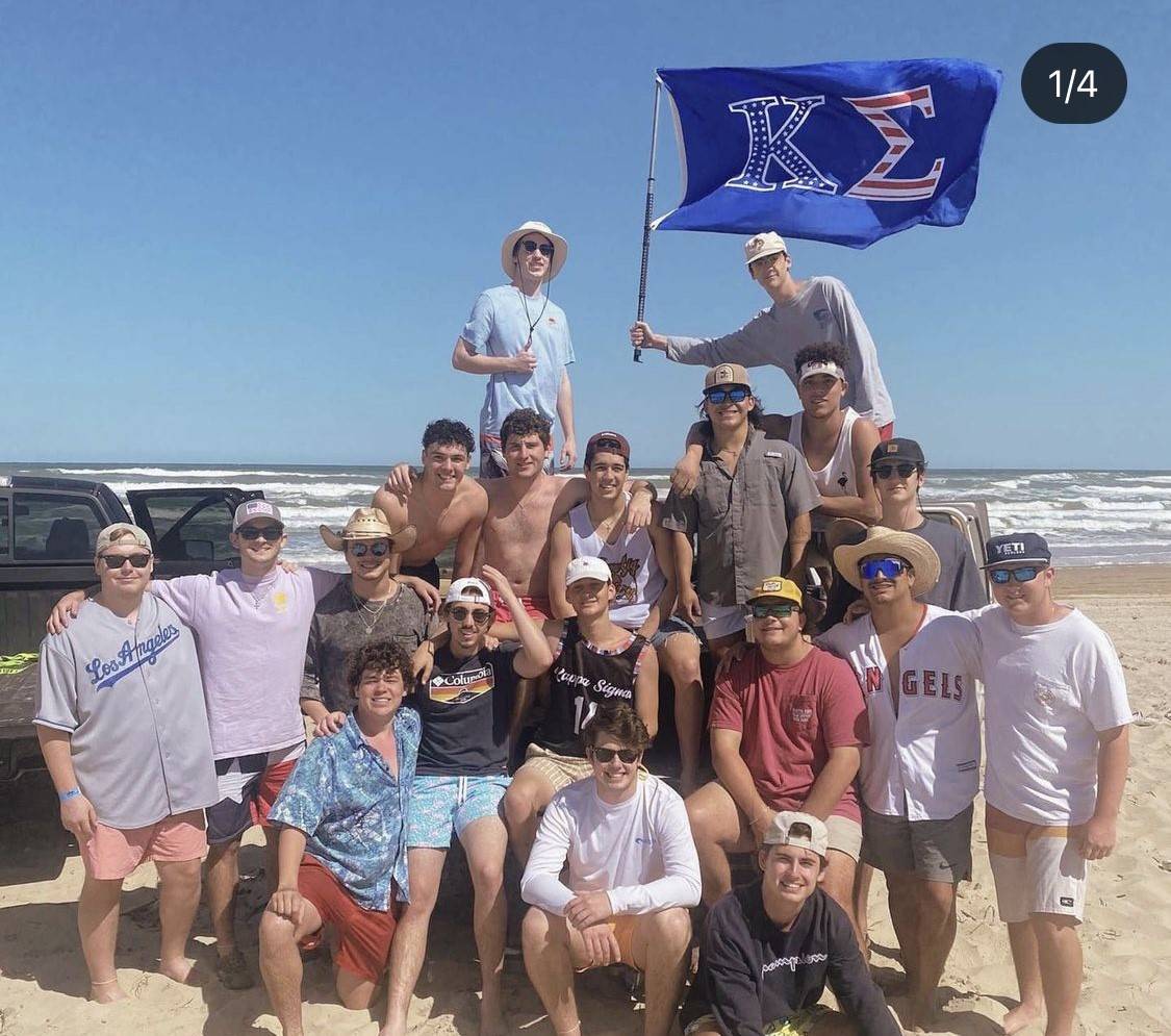 Fraternity men showcasing their flag and letters at the beach
