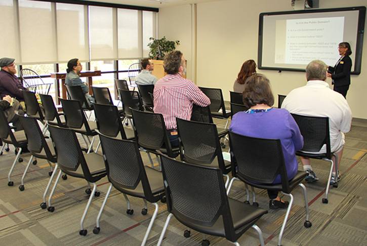 a professional gives a presentation from a projector screen to a group of people