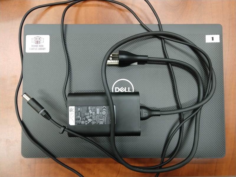 closed laptop with charger on top