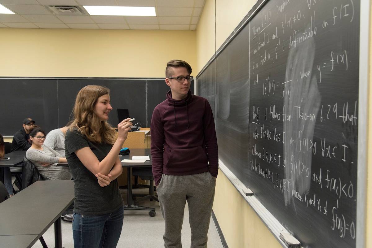 Students discussing math problem at a chalkboard