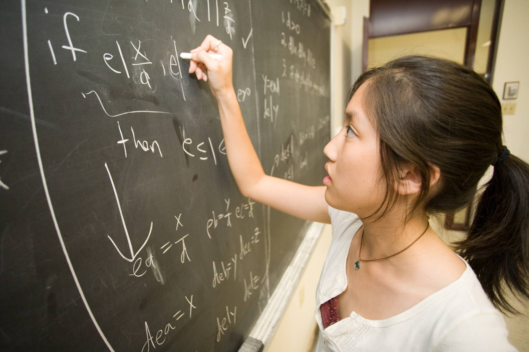 student writing on chalkboard