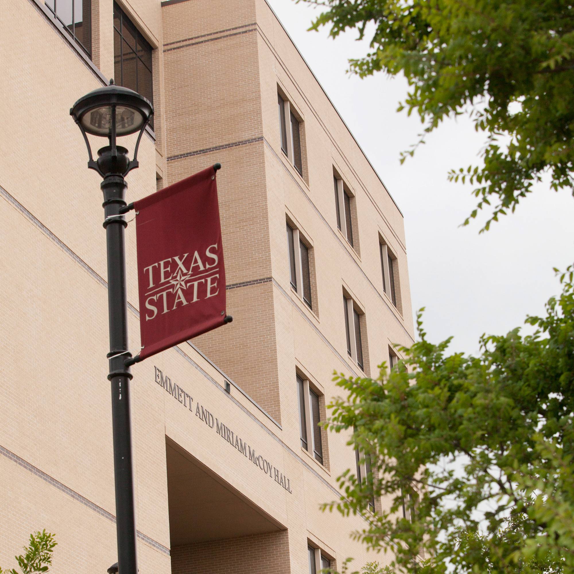 Front of McCoy Hall with Texas State banner on lamp post