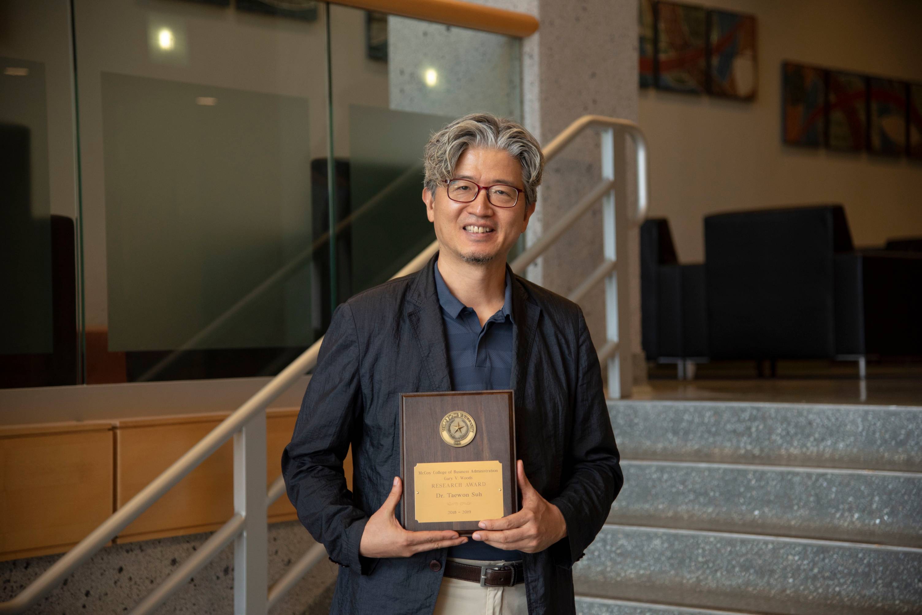 Professor holding award in McCoy Hall