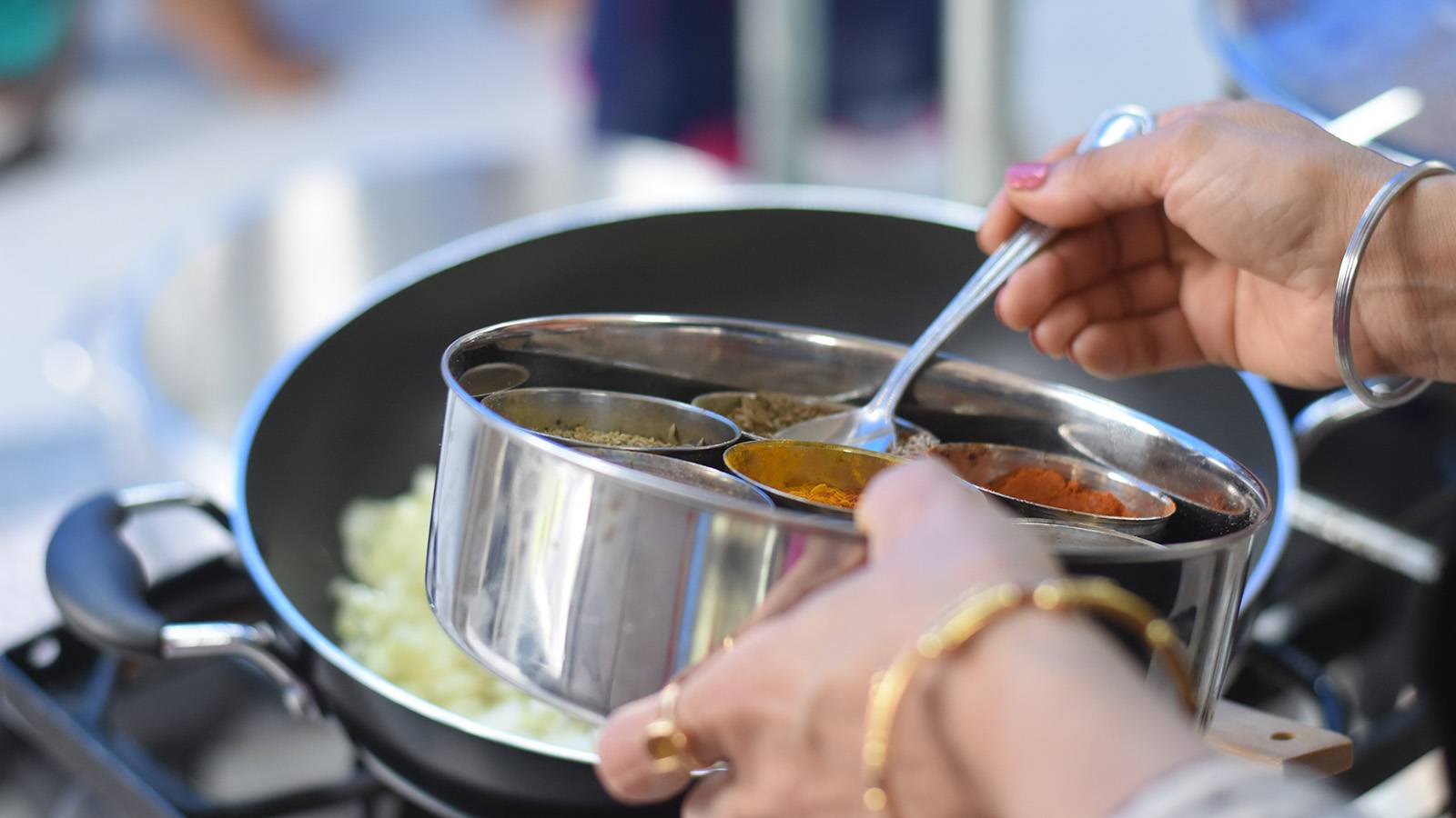 Person cooking food in a pan with spices
