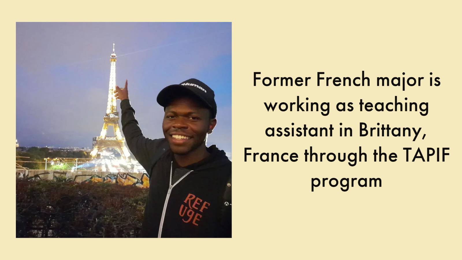 image: man wearing hoodie with "refuge" on it and baseball cap pointing at Eiffel Tower in background. Text: Former French major is working as teaching assistant in Brittany, France through the TAPIF program
