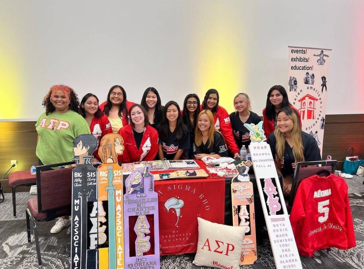 Women of Alpha Sigma Rho surrounded by organization memorabilia