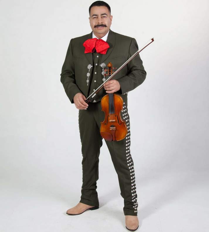 Miguel Guzman Standing hold a violin and bow in a Mariachi Traje